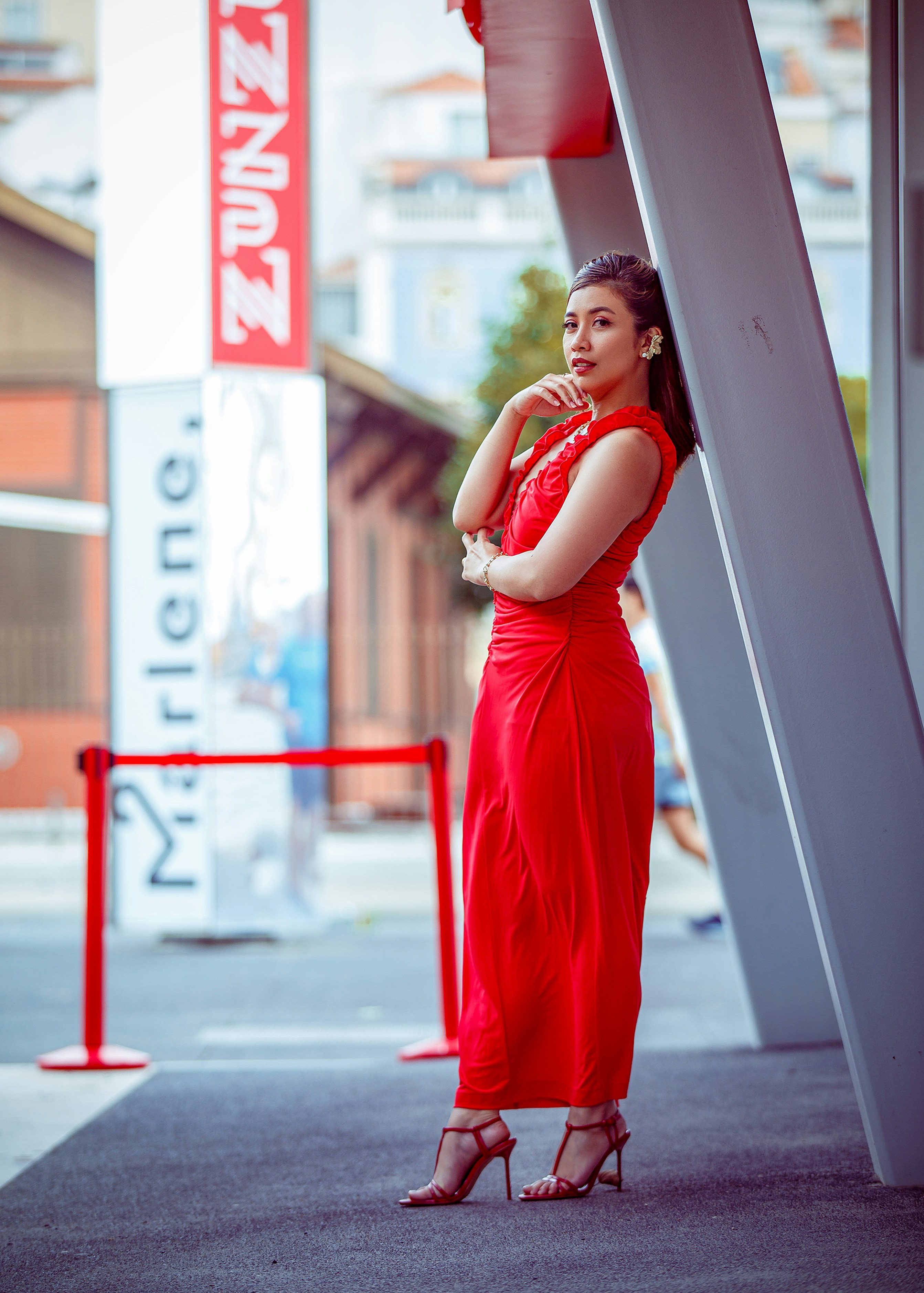 A woman in a red dress standing in front of a building