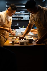 A couple of men standing in a kitchen preparing food