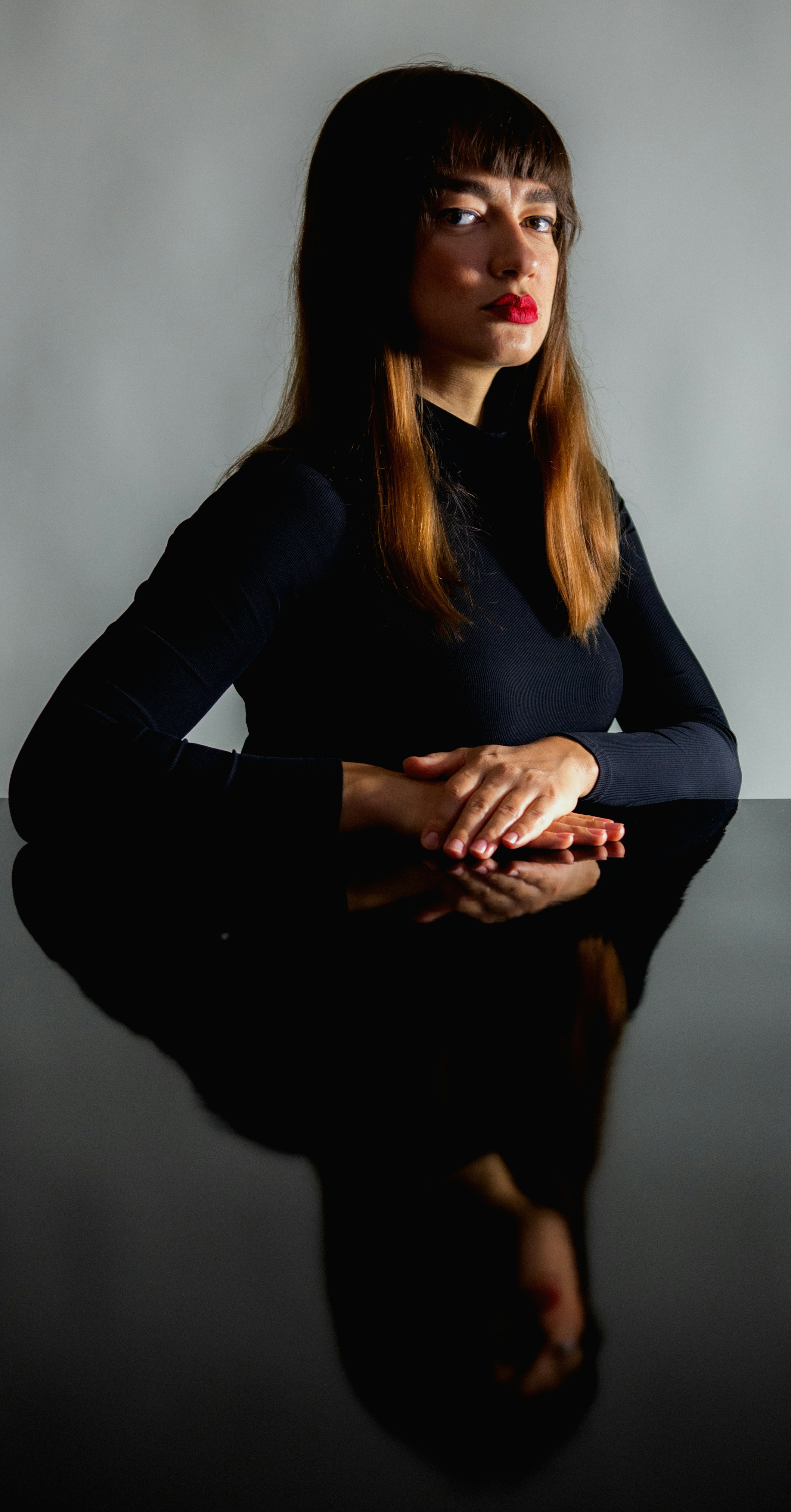 A woman sitting at a table with her hands on her knees