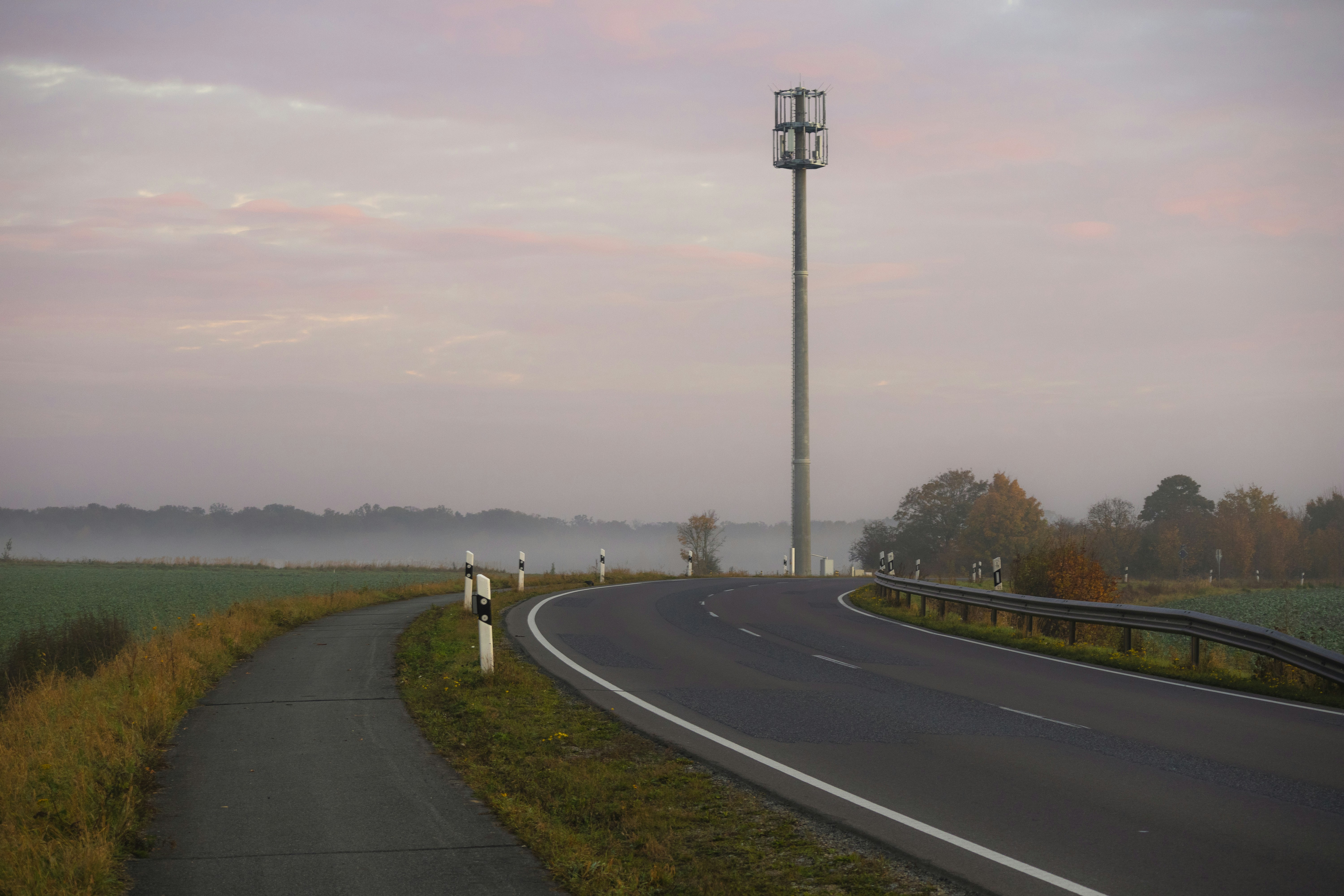 A curved road with a light pole in the background