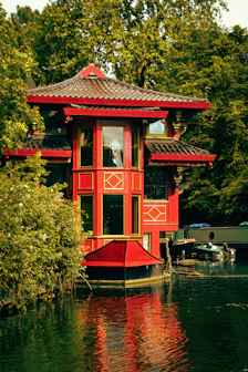 A red house sitting on top of a lake next to a forest