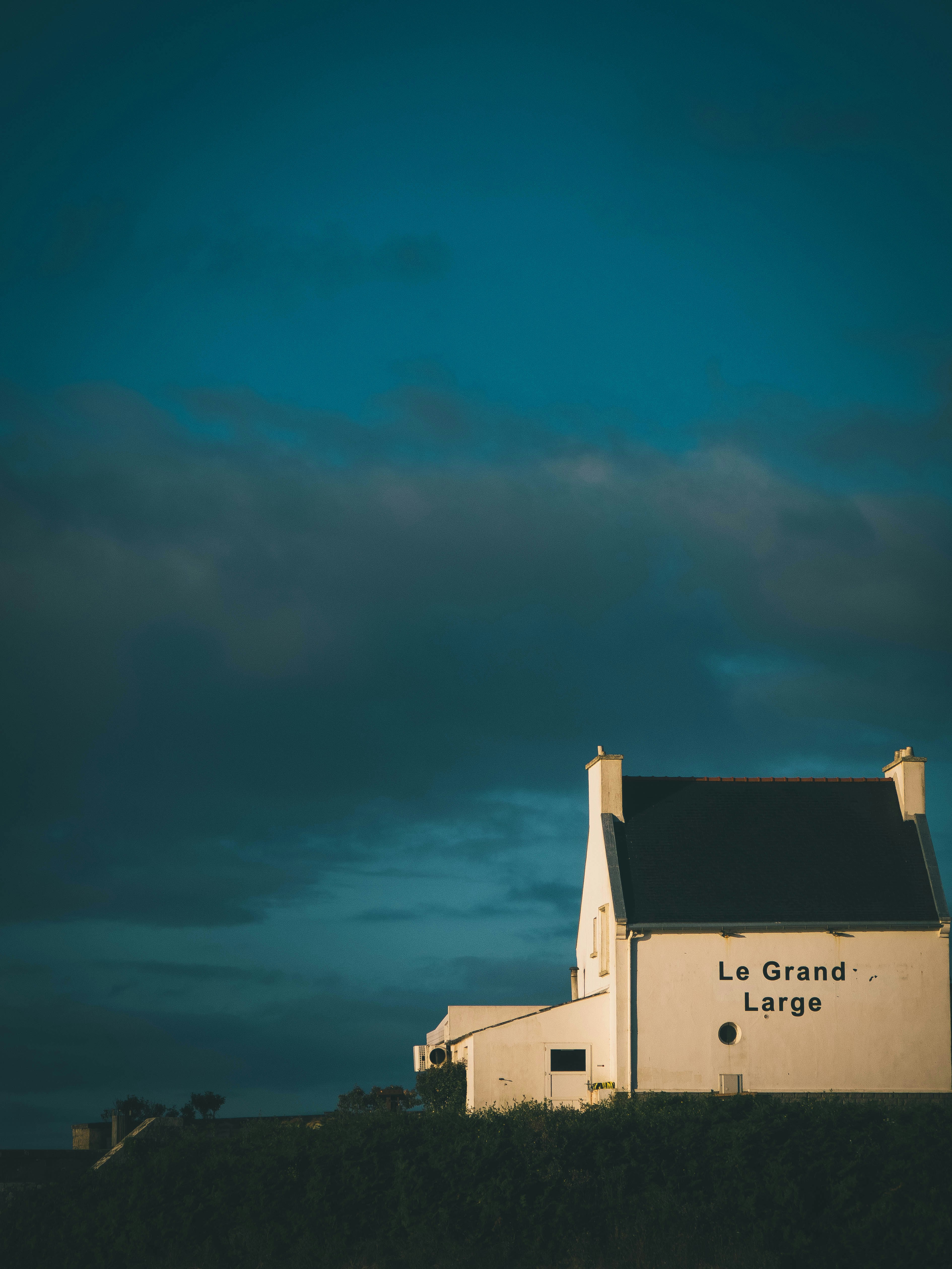 A white house sitting on top of a hill under a cloudy sky