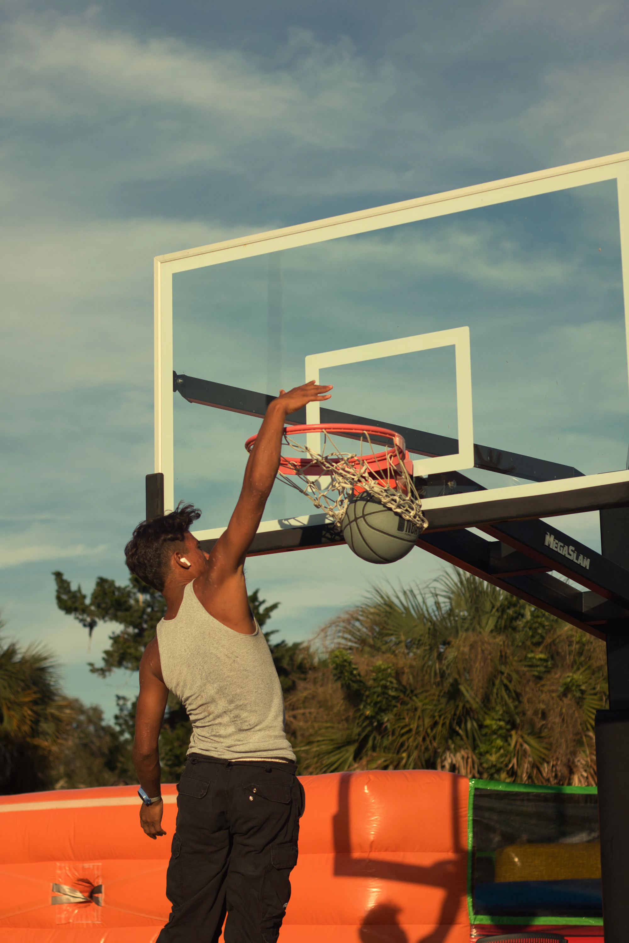 A basketball player reaching the hoop for a dunk.