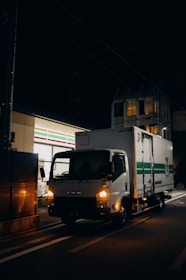 A delivery truck driving down a street at night