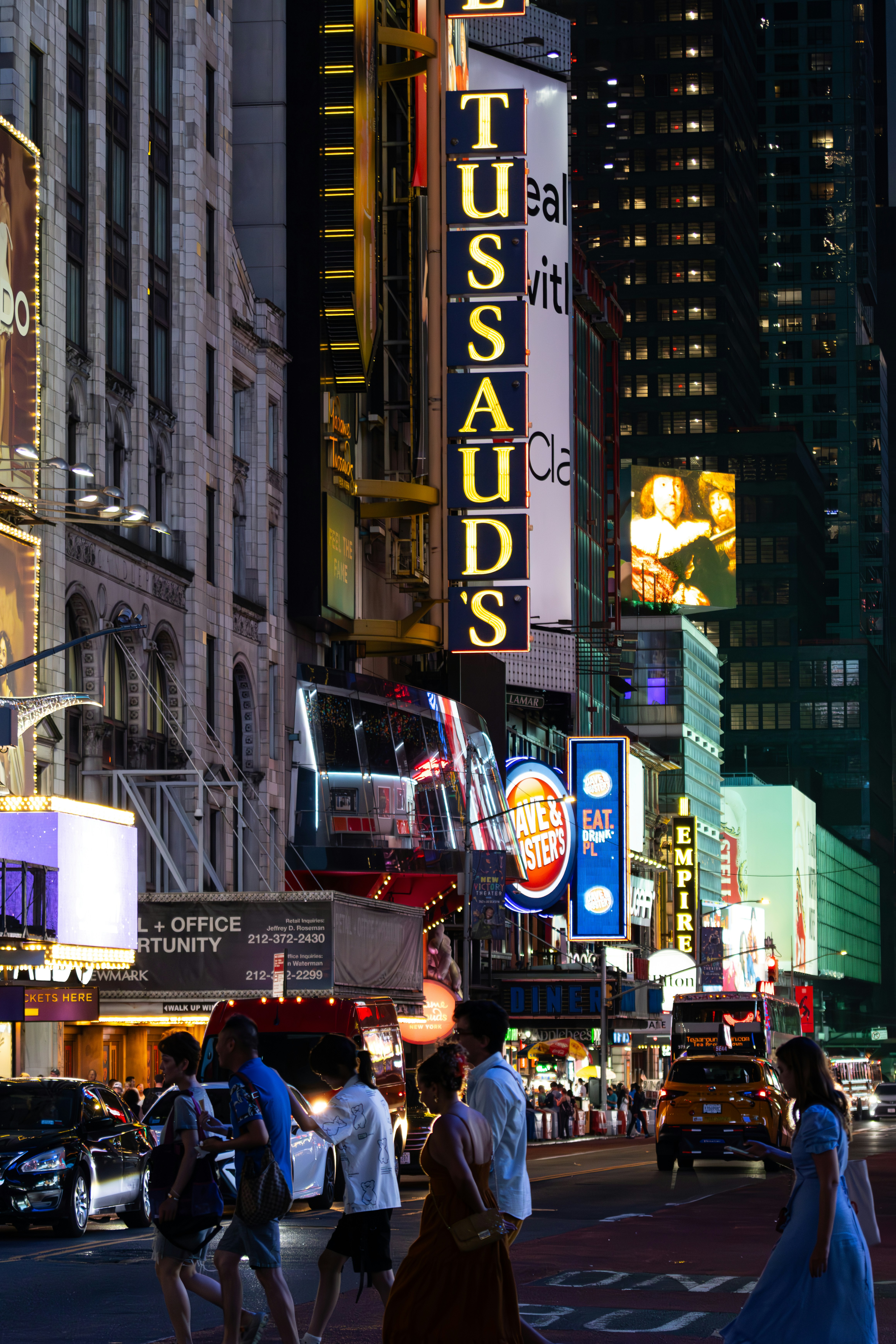 A group of people walking down a street next to tall buildings