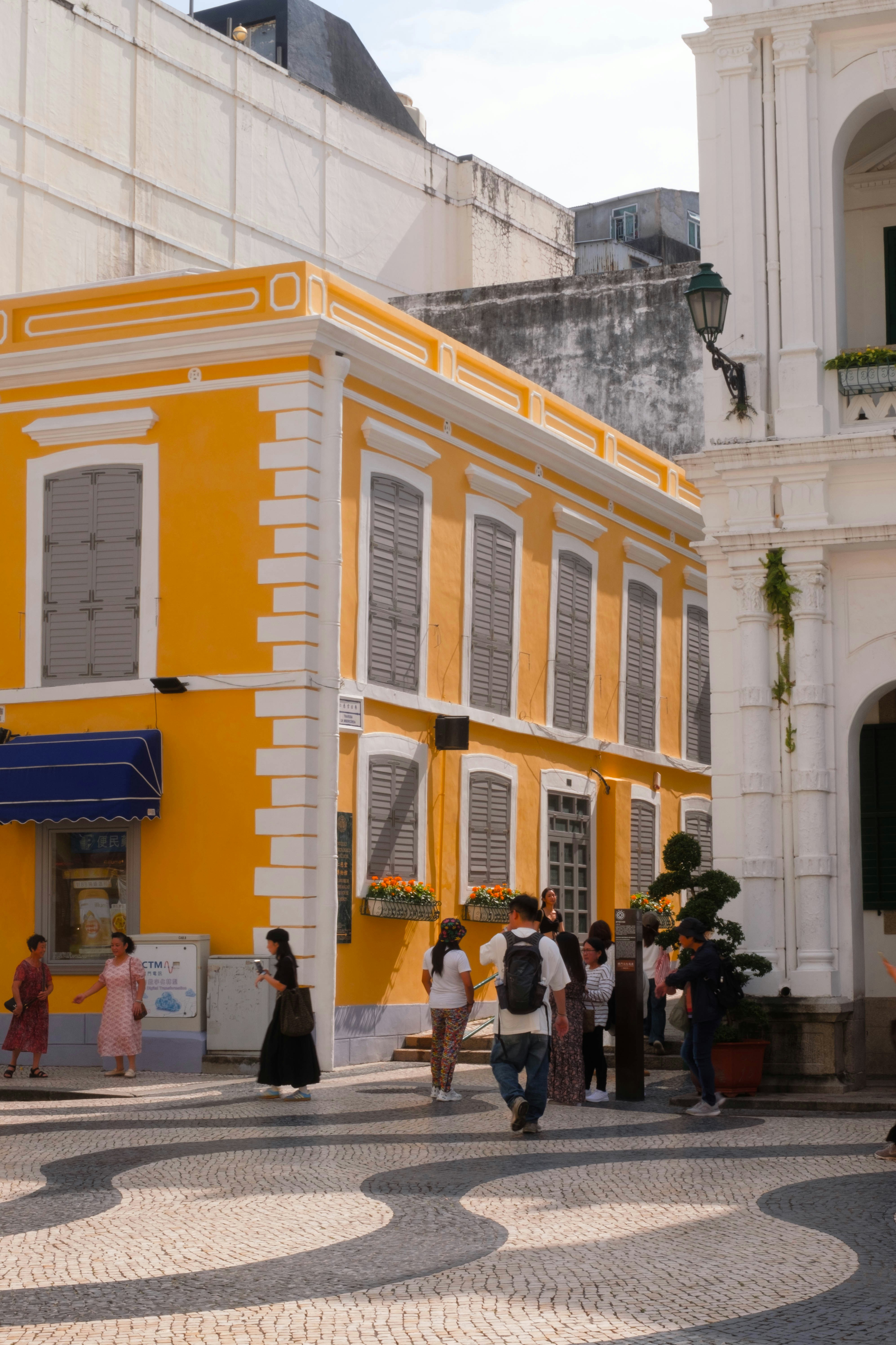A group of people walking in front of a yellow building