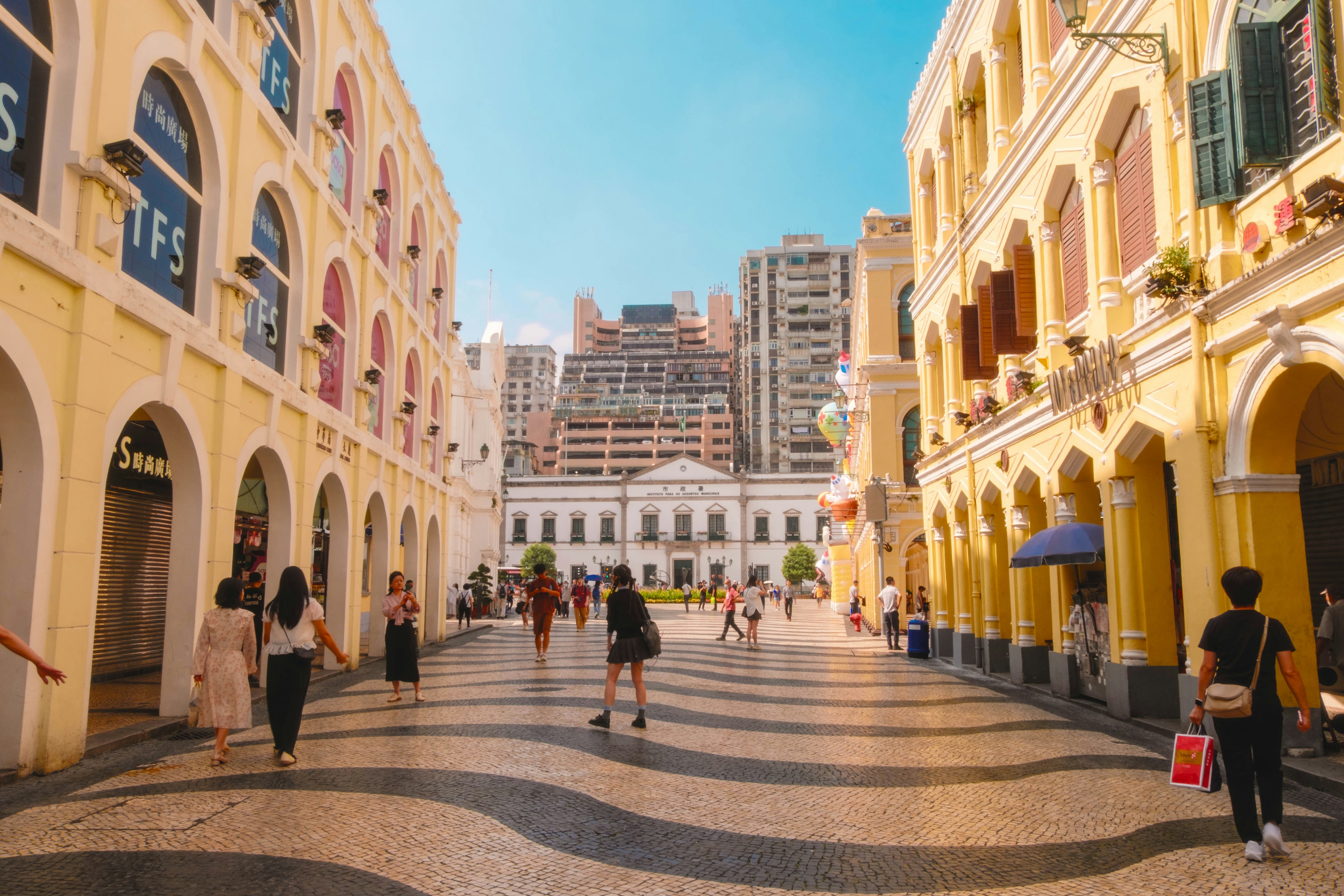 A group of people walking down a street next to tall buildings