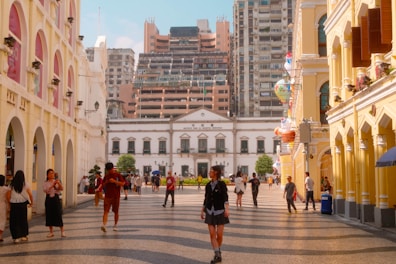 A group of people walking down a street next to tall buildings