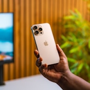 A person holding an iPhone in front of a TV