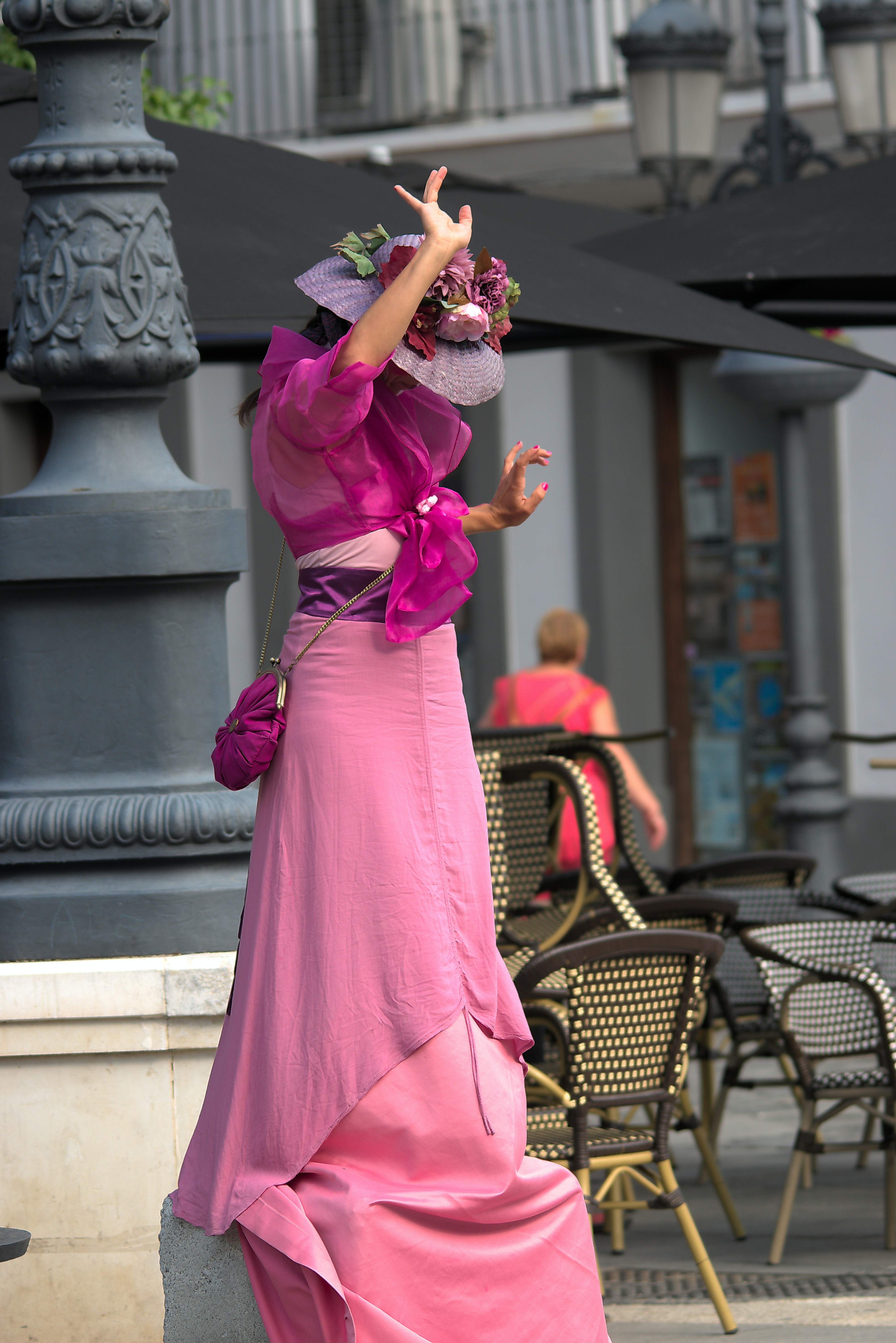 A woman in a pink dress and hat walking down the street