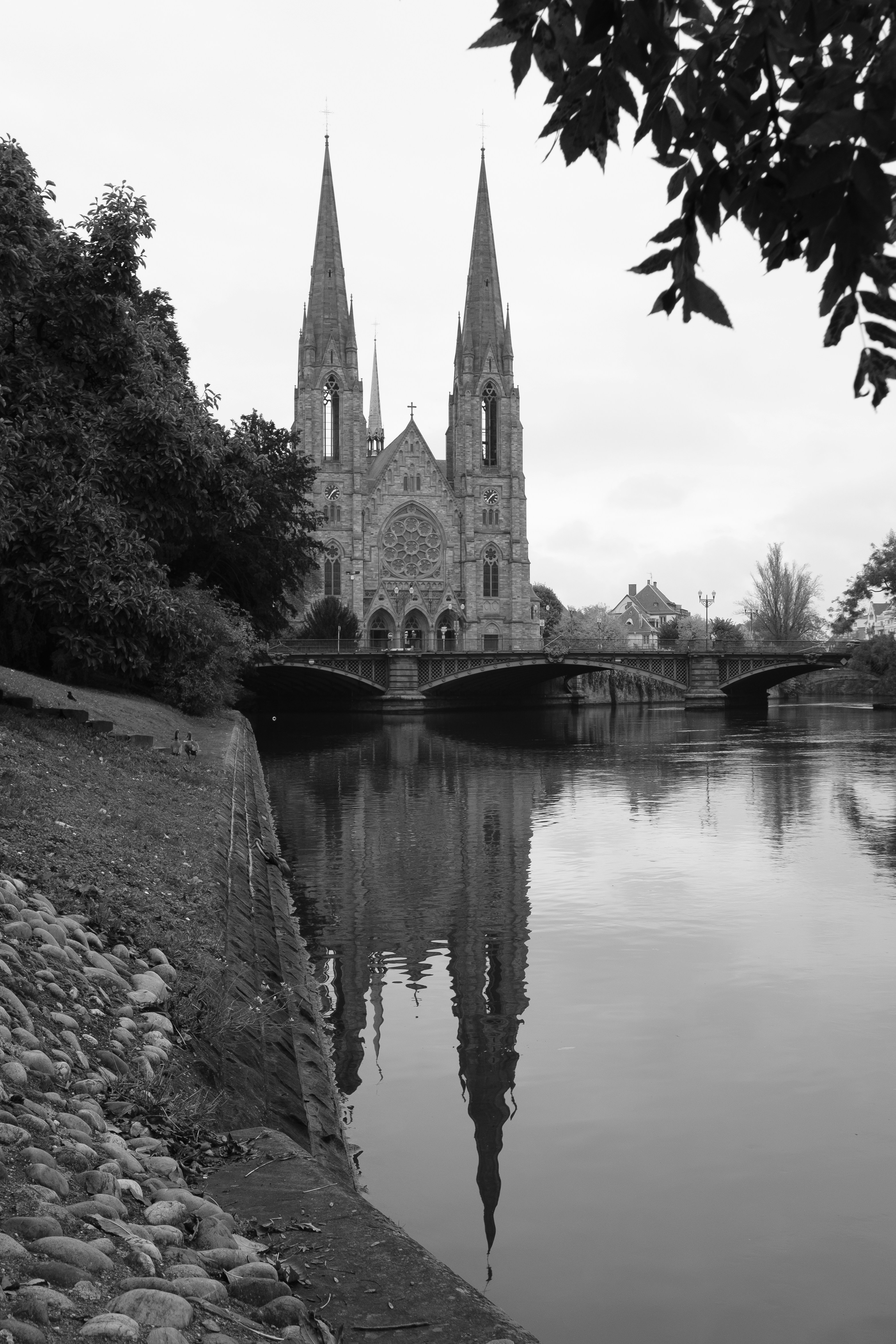 A black and white photo of a river with a church in the background