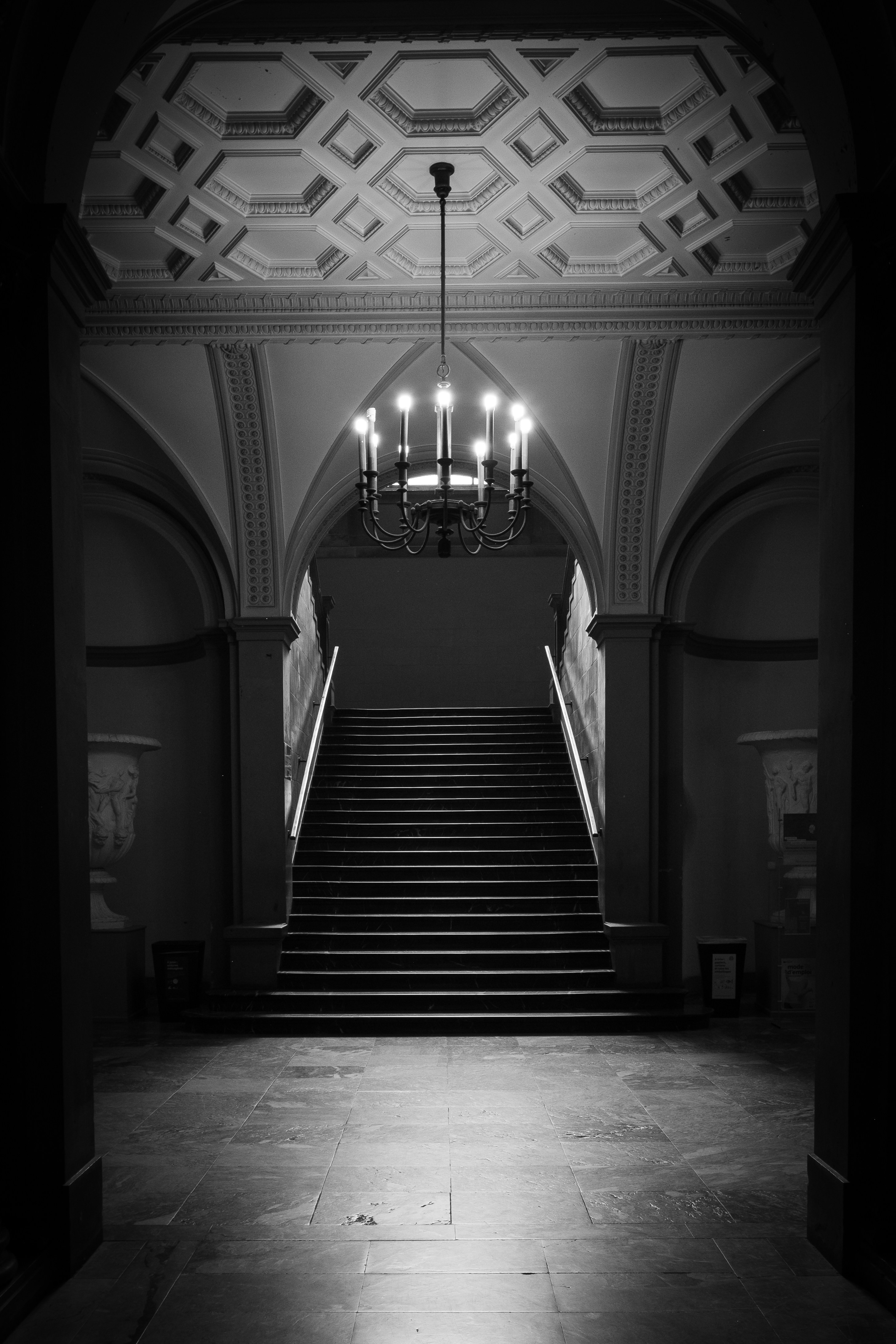 A black and white photo of a staircase and chandelier