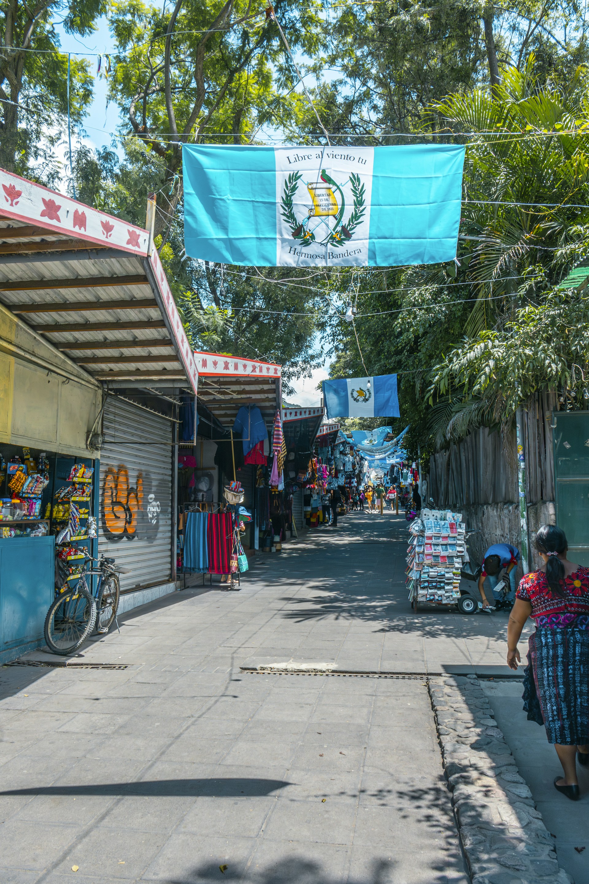 A woman walking down a street next to a store