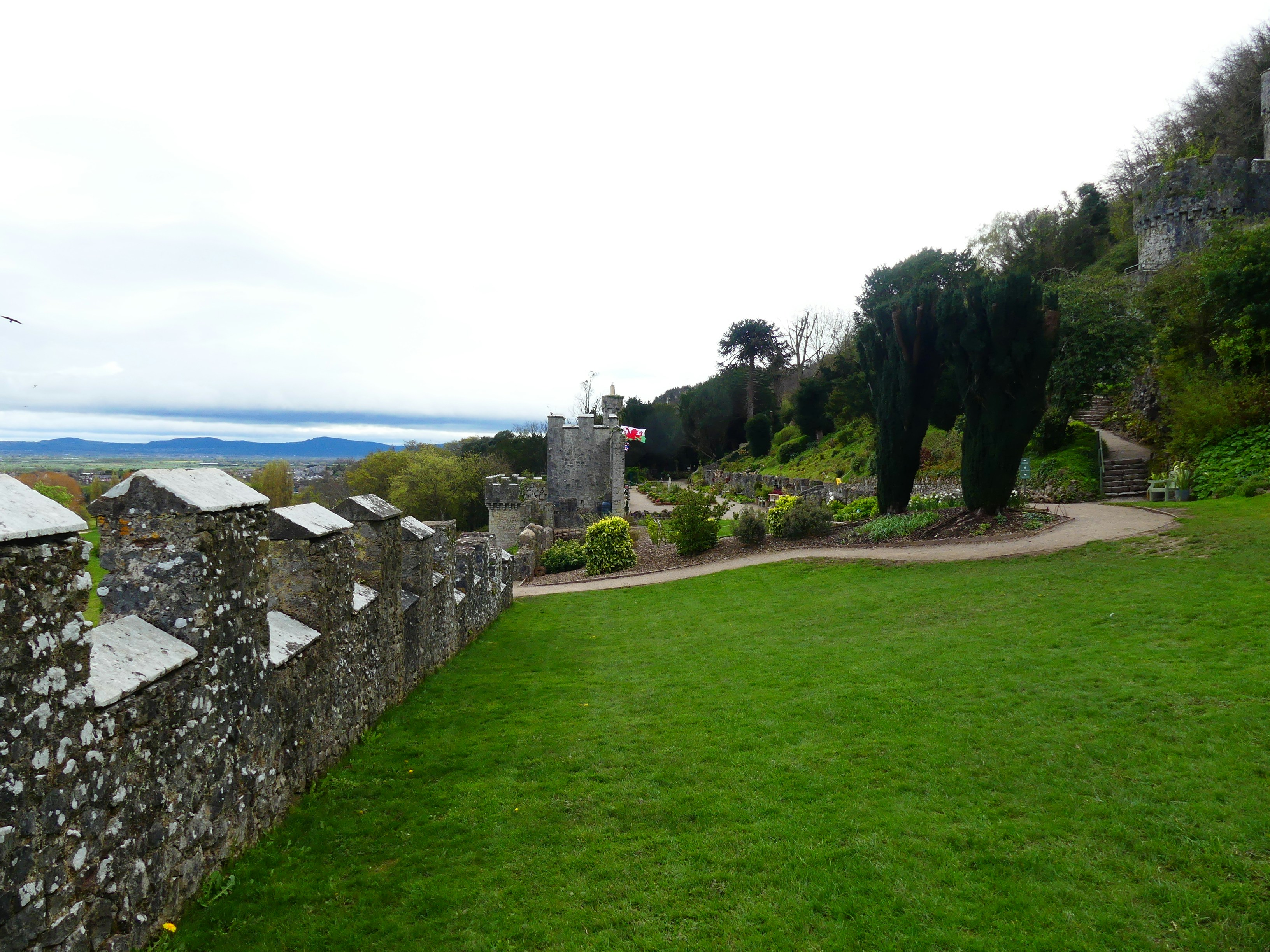 A stone wall in a grassy area next to a building