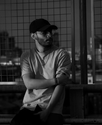 A black and white photo of a man sitting on a bench