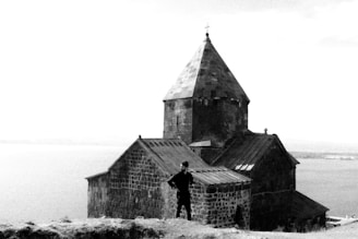 A black and white photo of a man standing in front of a church