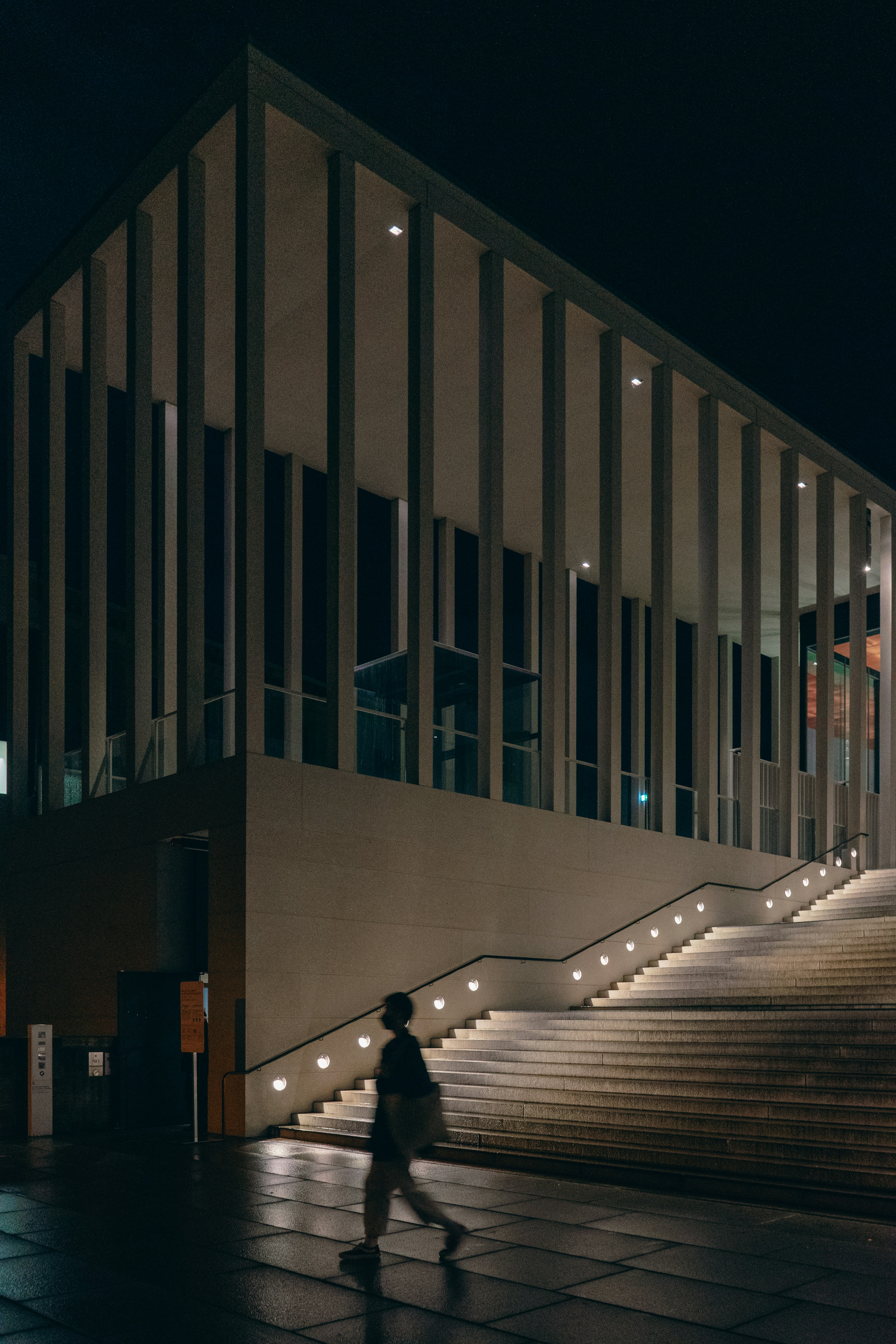 A person walking down a sidewalk next to a building