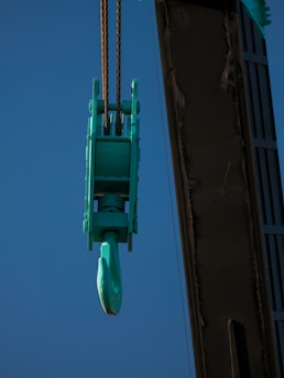 A crane is lifting a green object in the air