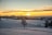 The sun is setting over a snowy field