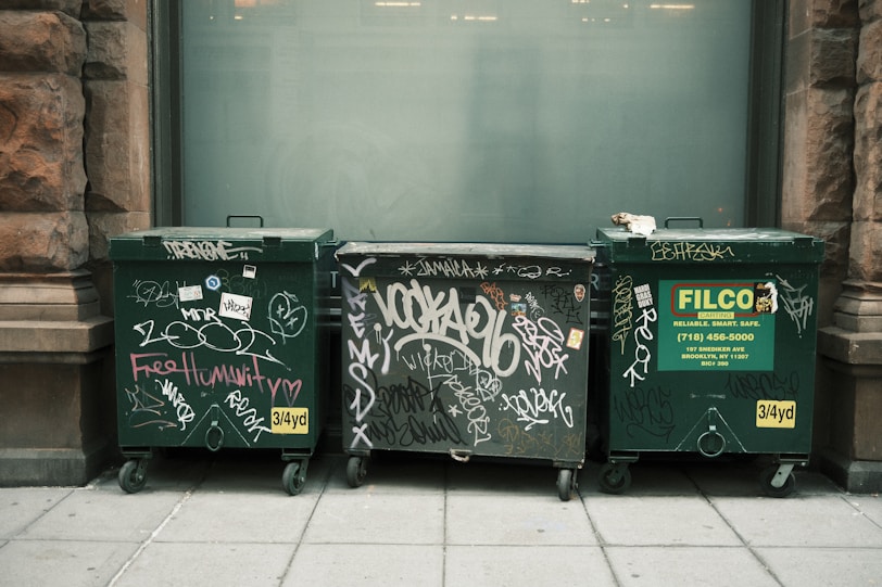 A row of trash cans sitting on the side of a building