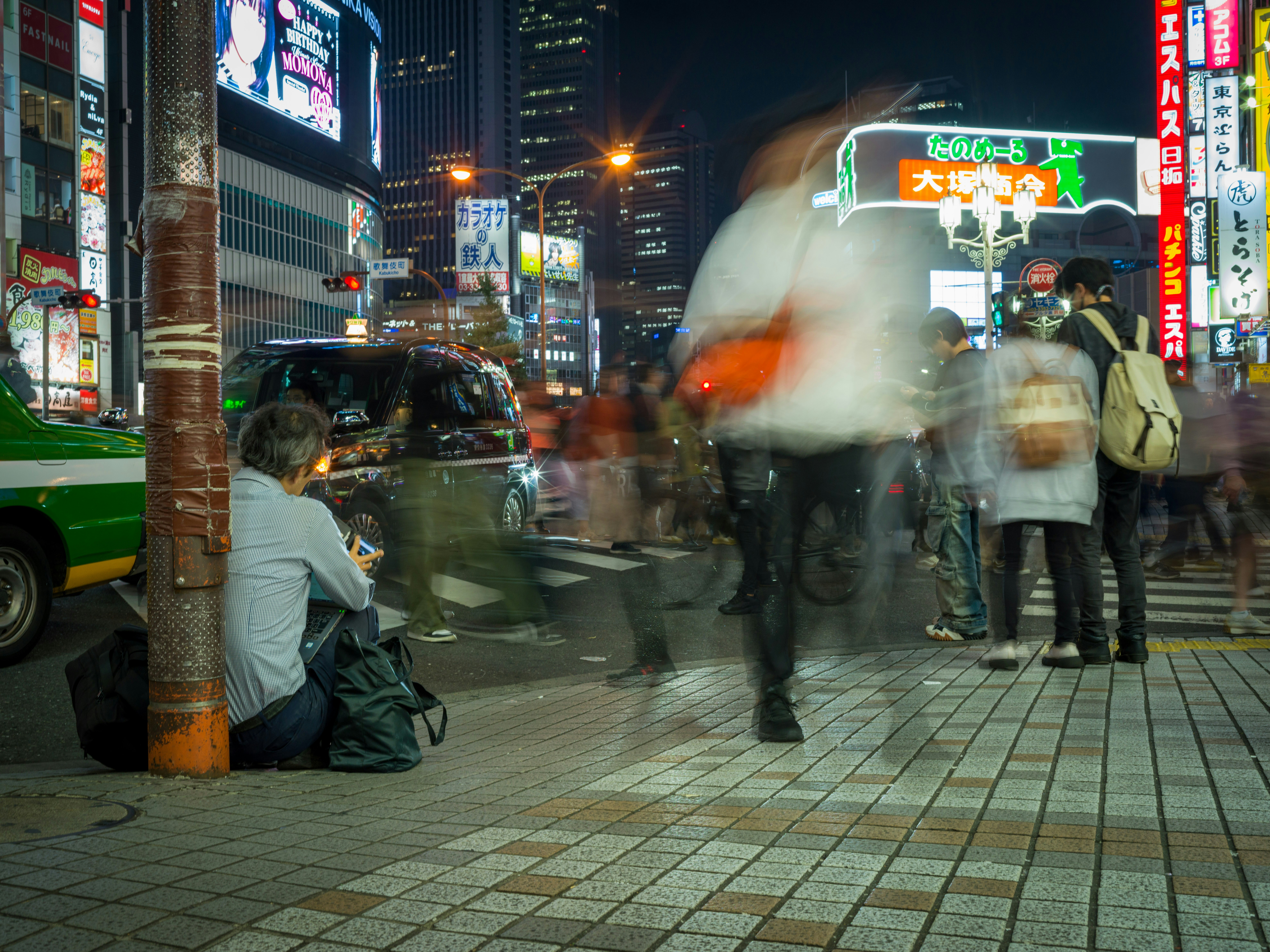A group of people standing on a street next to tall buildings