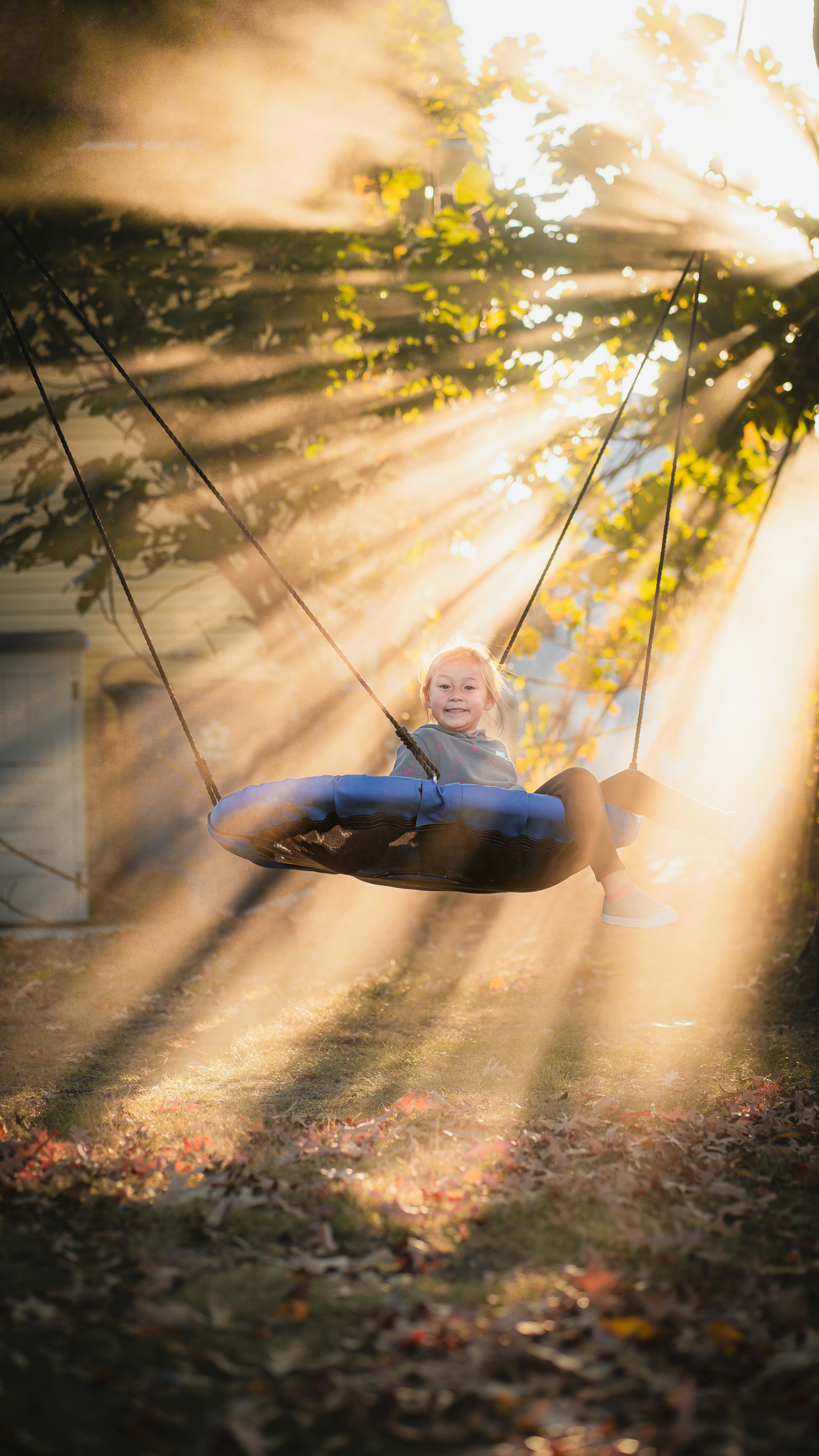 A little girl sitting on a swing in the sun