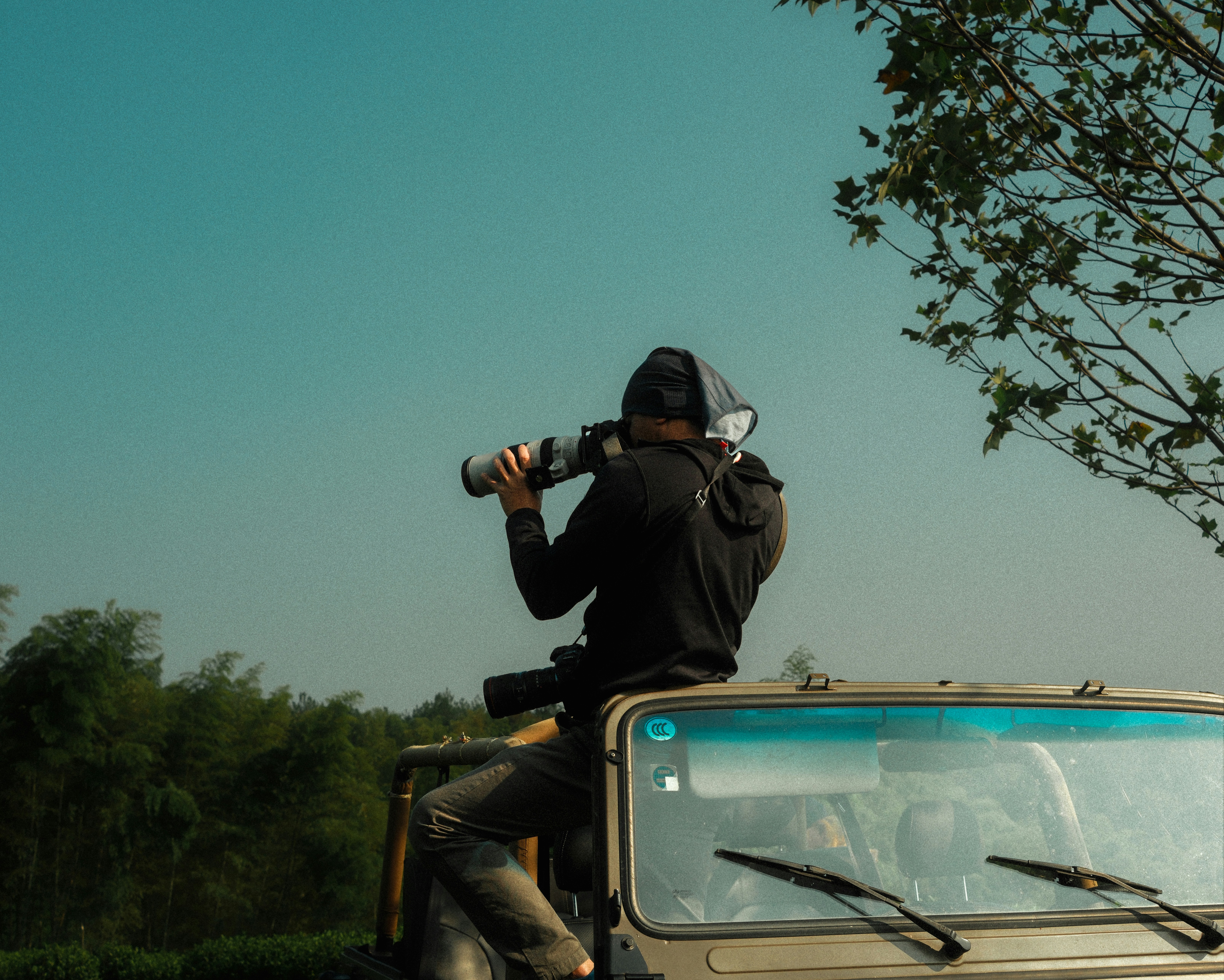 A man sitting on the back of a truck taking a picture