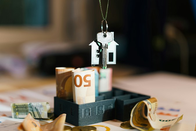 Model house hanging over a pile of money, representing Las Vegas home sellers adjusting their asking price in a softer market