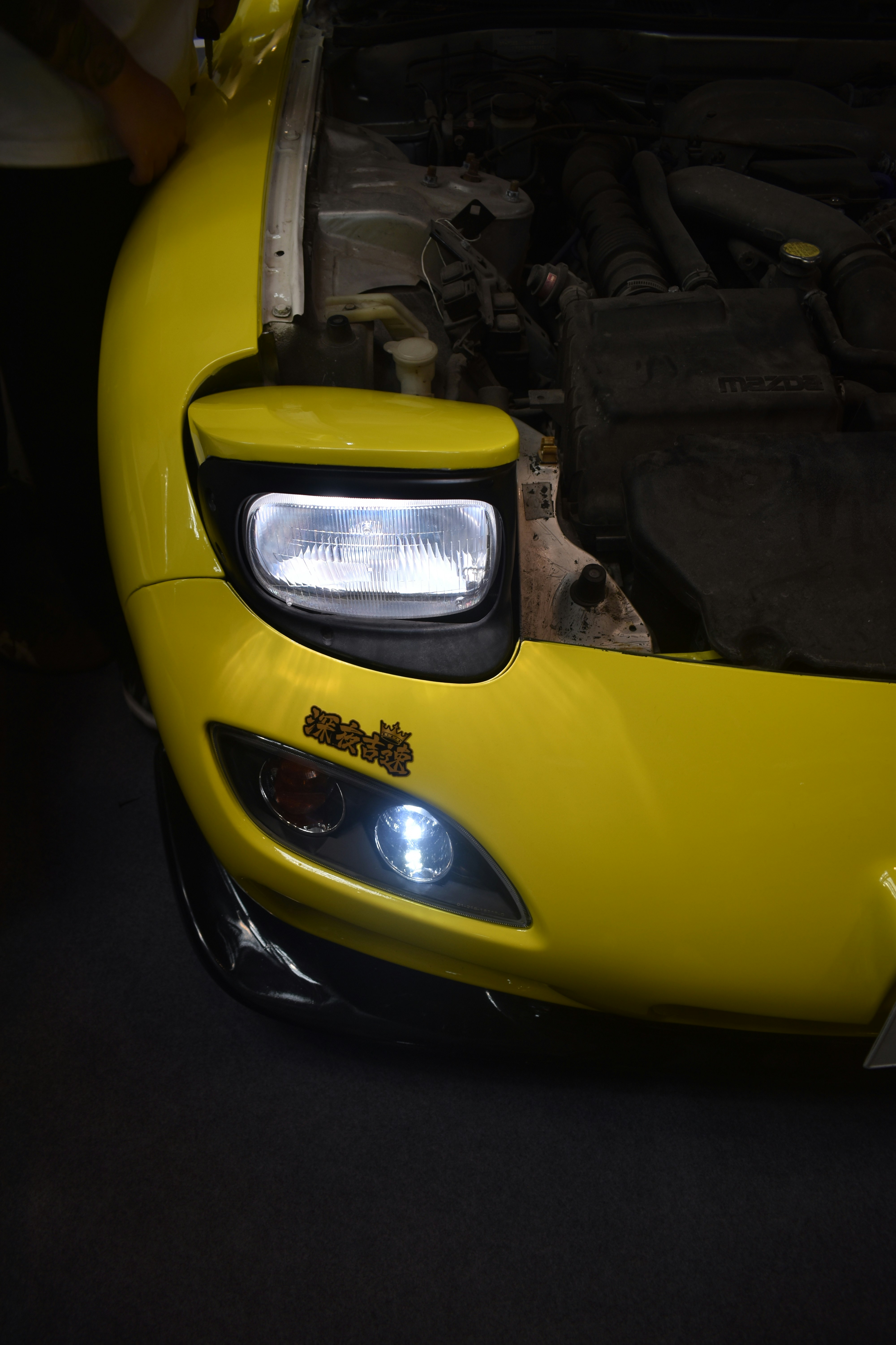 A yellow sports car with its hood open