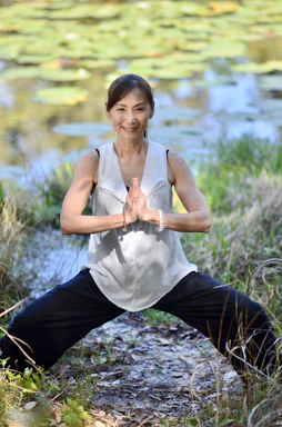 Une femme fait du yoga et médite devant un plan d'eau