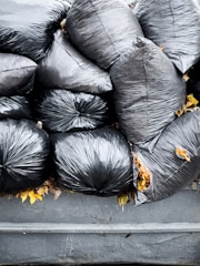 A pile of black bags sitting on top of a trash can