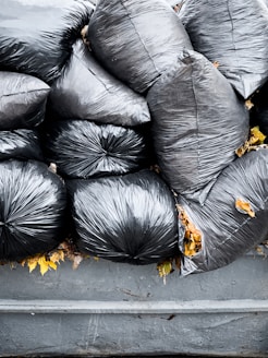 A pile of black bags sitting on top of a trash can