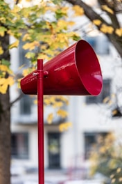 A red mailbox sitting next to a tree