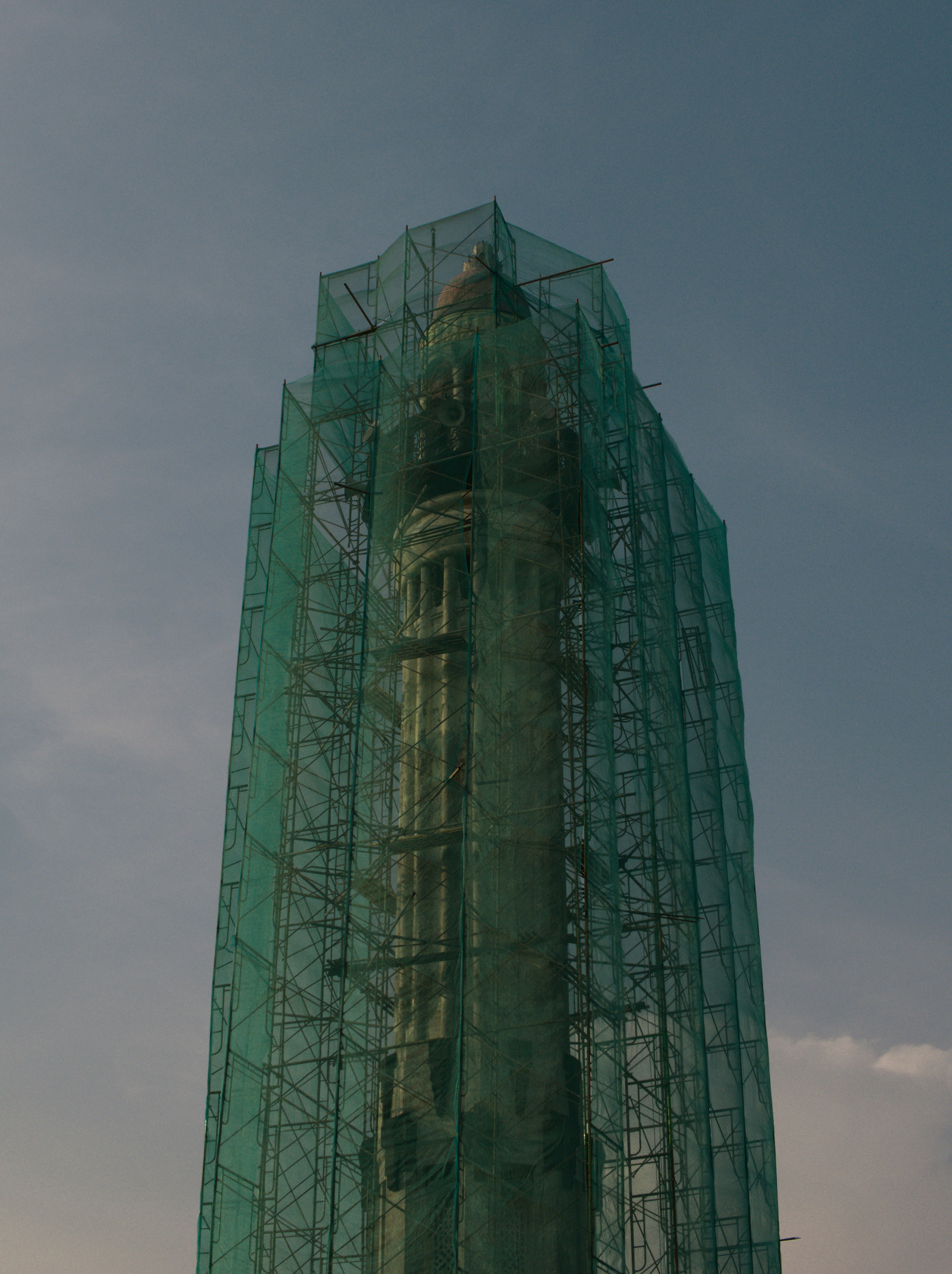 A very tall green building with a clock on it's side