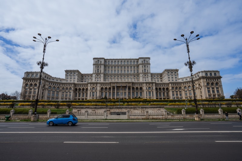 A blue car parked in front of a large building