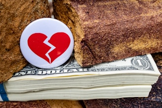 A broken heart on top of a stack of money