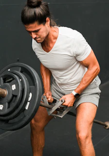 A man holding a barbell while standing in a gym