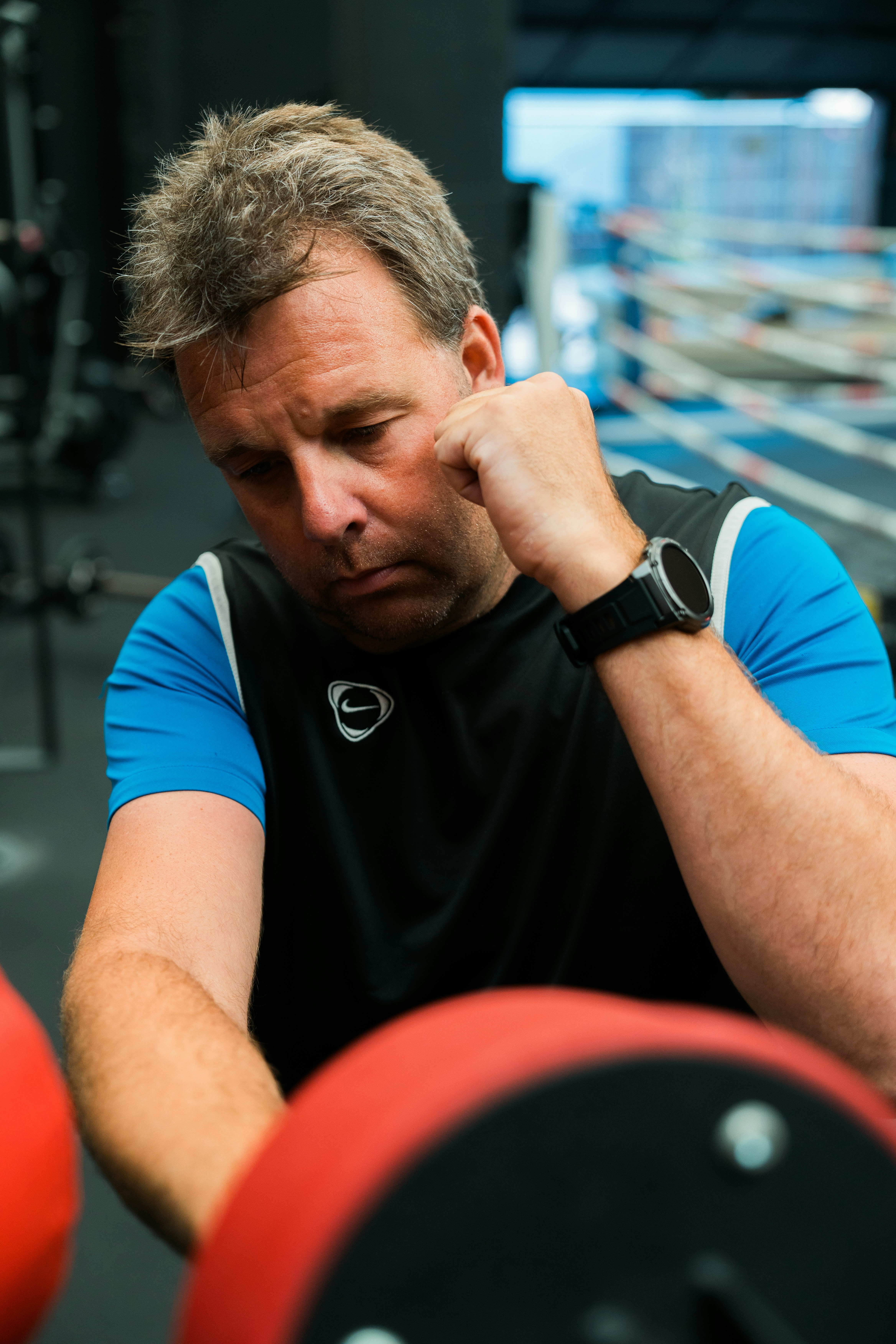 A man sitting in a gym holding a barbell
