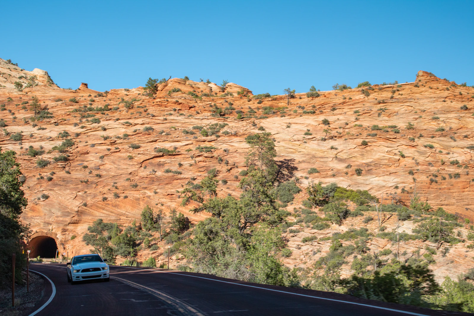 A car exits a tunnel beneath the cliffs of Zion National Park