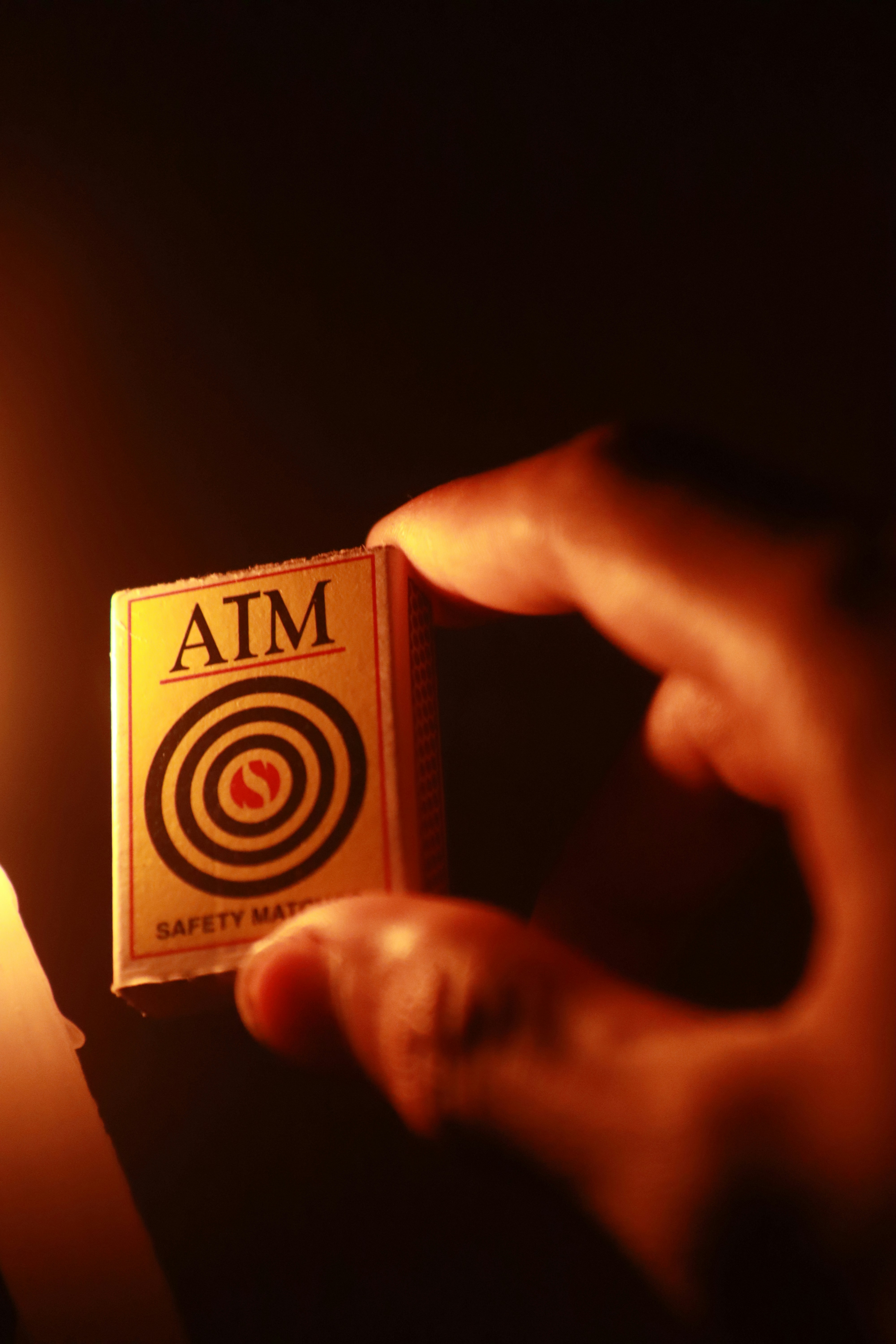 A person holding a match in front of a lit candle