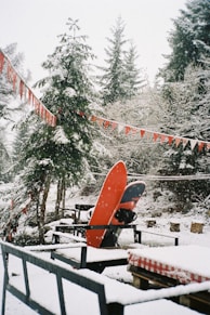 A red snowboard sitting on top of a snow covered ground