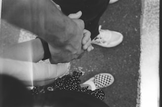 A black and white photo of two people holding hands