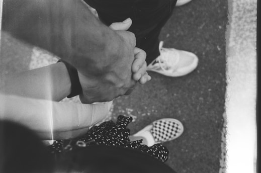 A black and white photo of two people holding hands