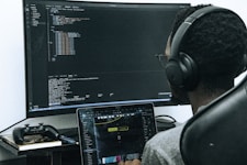 A man sitting in front of a computer wearing headphones