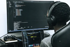 A man sitting in front of a computer wearing headphones