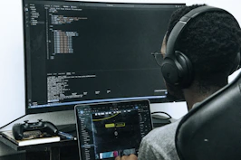 A man sitting in front of a computer wearing headphones