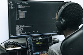 A man sitting in front of a computer wearing headphones