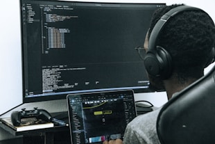 A man sitting in front of a computer wearing headphones