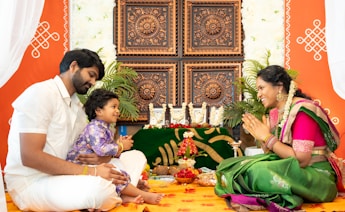A family sitting on the floor in front of a decorated wall