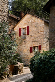 A stone house with red shutters and red shutters